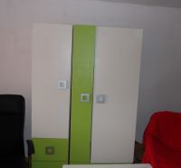 Šatní skříň s barevnými dveřmi a černé křeslo v 2pokojovém bytě.