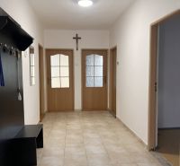 Chodba v rodinném domě s dlažbou, dřevěnými dveřmi a věšákem.