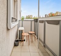 Balkon se dvěma oranžovými židlemi v 2-pokojovém bytě s výhledem na město.