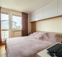 Ložnice s růžovou přikrývkou ve 3-pokojovém bytě, vybavená podlahou s dřevěným dekorem.