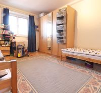 Ložnice s velkou postelí, skříní, kobercem a podlahou s dřevěným dekorem v 2-pokojovém bytě.