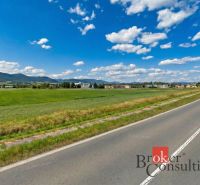Hliník nad Hronom, Pozemky - komerční, zelené louky u cesty obklopené kopci a budovami.