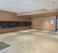 Vstupní hala s poštovními schránkami a dřevěným obkladem stěn ve 4pokojovém bytě.