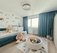 Dětský pokoj ve 4-pokojovém bytě s podlahou s dřevěným dekorem, hračkami a nástěnnou dekorací.