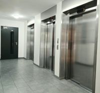 Chodba se čtyřmi kovovými výtahy a šedou dlažbou ve 4-pokojovém bytě.