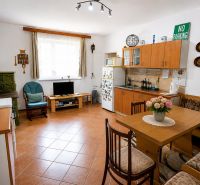Kuchyně v rodinném domě s krbem, nábytkem a dekoracemi, podlaha s dřevěným dekorem.
