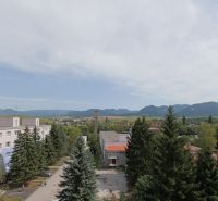 Pohled na ulici Mudrochova v Rajci s výhledem na přírodu a budovy.