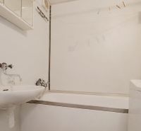 Koupelna v 2-pokojovém bytě s vanou, umyvadlem a pračkou.