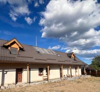 Rodinný dům v Hronské Dúbravě s velkou střechou a skalnatým chodníkem v zahradě.