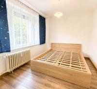 Ložnice s podlahou s dřevěným dekorem a postelí ve 3-pokojovém bytě.