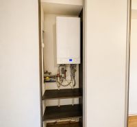 Vestavěná skříň s kotlem v 3-pokojovém bytě, podlaha s dřevěným dekorem.