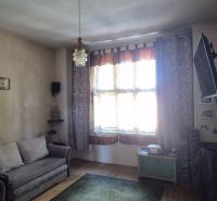 Obývací pokoj v 2pokojovém bytě s pohovkou, TV a podlahou s dřevěným dekorem.