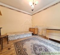 Pokoj s postelí, židlí a koberci, podlaha s dřevěným dekorem, rohový nábytek.