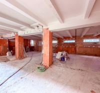 Prostorné obchodní prostory s betonovými stěnami a podlahou, příprava na rekonstrukci.