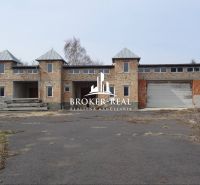 Nedokončená budova v prostředí Méra se skladovými a výrobními prostory, bez vnější úpravy.