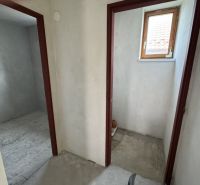 V rodinném domě se nacházejí dvě místnosti s betonovou podlahou a malým oknem.