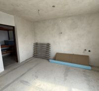 Interiér rodinného domu s nedokončenými stěnami a podlahou, s materiály na podlaze.