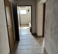 Chodba v rodinném domě s dlažbou a oknem, bez viditelného nábytku.