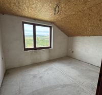 Pohled do prázdné místnosti rodinného domu se střešním oknem a betonovou podlahou.