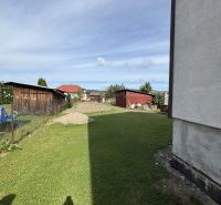 Travnatý dvůr u rodinného domu v Plavnici s výhledem na další zástavbu.