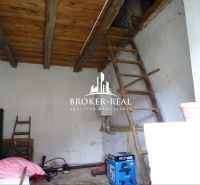 Interiér rodinného domu s dřevěným stropem a žebříkem, zařízený nářadím a bednami.