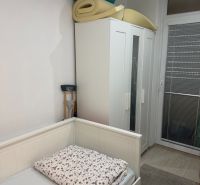 Pokoj s postelí, šatní skříní a srolovanými matracemi v 2-pokojovém bytě.