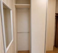 Vestavěná šatní skříň s posuvnými dveřmi a podlahou s dřevěným dekorem v 2pokojovém bytě.