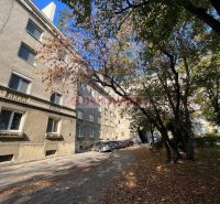 Bytový dům na Miletičově ulici v Bratislavě - Ružinově, obklopený stromy a auty.