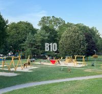 Dětské hřiště na Měsíční ulici v Bratislavě II plné barevného vybavení a zeleně.