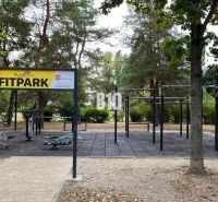 Fitpark s venkovním posilovacím zařízením, obklopený zelení v parku.