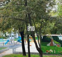 Park s dětským hřištěm mezi stromy v Bratislavě II, na ulici Měsíční.