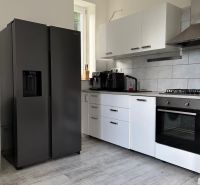 Kuchyně s podlahou s dřevěným dekorem a moderním vybavením v 2-pokojovém bytě.