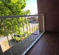 Balkon s výhledem na ulici v Galantě z 2pokojového bytu, vedle stromů.
