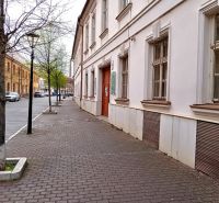 Ulice Františkánská v Trnavě s historickými budovami a stromy u kanceláří.