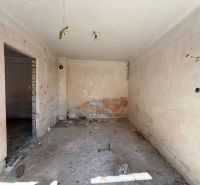 Pokoj v rodinném domě před rekonstrukcí s odkrytými stěnami a podlahou.