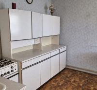 Kuchyně v rodinném domě s plynovým sporákem a podlahou s dřevěným dekorem.