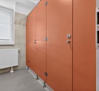 Oranžové kabinky s dveřmi na veřejných toaletách v kancelářích.