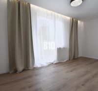 Světlý pokoj s podlahou s dřevěným dekorem a velkým oknem ve 4pokojovém bytě.
