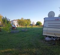 Karavan v zahradách na Tatranské 201 ve Zlatých Moravcích obklopený stromy a trávou.