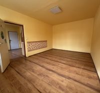 Pokoj s podlahou s dřevěným dekorem v 1-pokojovém bytě se žlutými stěnami.