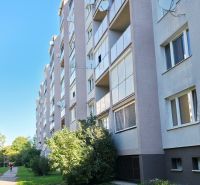 Exteriér panelového domu v Trnavě se zelení a chodníkem k 3-pokojovému bytu.