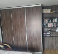 Skříň a knihovna v 3-pokojovém bytě, s podlahou s dřevěným dekorem.
