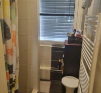 Koupelna s kachličkovanou sprchou, závěsem a oknem v 3-pokojovém bytě.