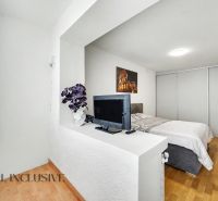 Světlá ložnice s televizí, postelí a podlahou s dřevěným dekorem v rodinném domě.