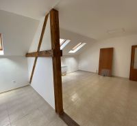 Podkrovní kancelář s dřevěnými trámy a šikmými okny, podlaha s dřevěným dekorem.
