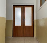 V kancelářích jsou dvoukřídlé dveře se zasklením a světle hnědými stěnami.