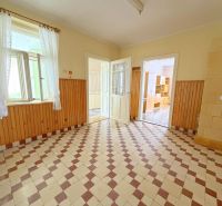 Interiér rodinného domu, světlá místnost s dlaždicovou podlahou a dřevěným obložením stěn.