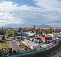 Panorama Kežmarku s garážemi, pohled na blízké Tatry a rozmanitou architekturu města.