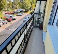 Balkon s výhledem na stromy a auta na Nádražní v Partizánském, prostor 3pokojového bytu.