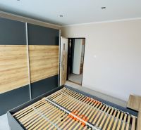 Ložnice s vestavěnou skříní a postelí v 3pokojovém bytě s podlahou s dřevěným dekorem.